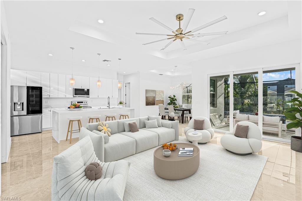 Living room with a raised ceiling, recessed lighting, light tile patterned flooring, and a ceiling fan