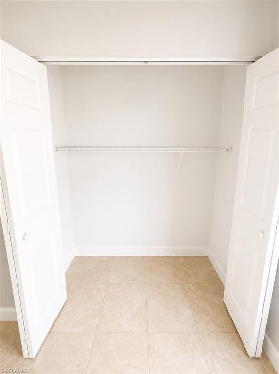 Closet space featuring bi-fold doors, neutral wall paint, a wire shelving system, and tiled flooring