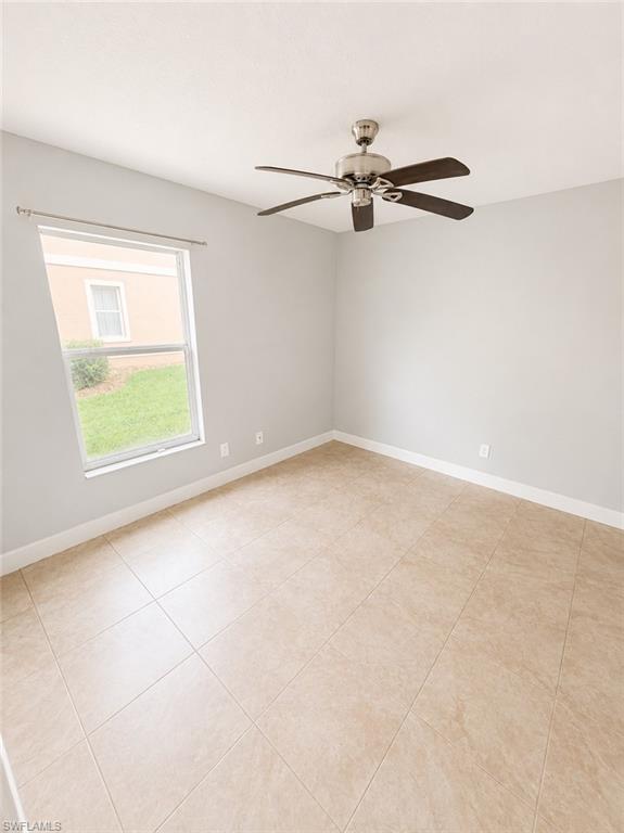 Spacious interior room featuring light neutral wall paint and large format tile flooring