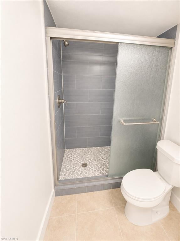 Tiled shower with frosted sliding glass doors, pebble flooring, and brushed nickel fixtures