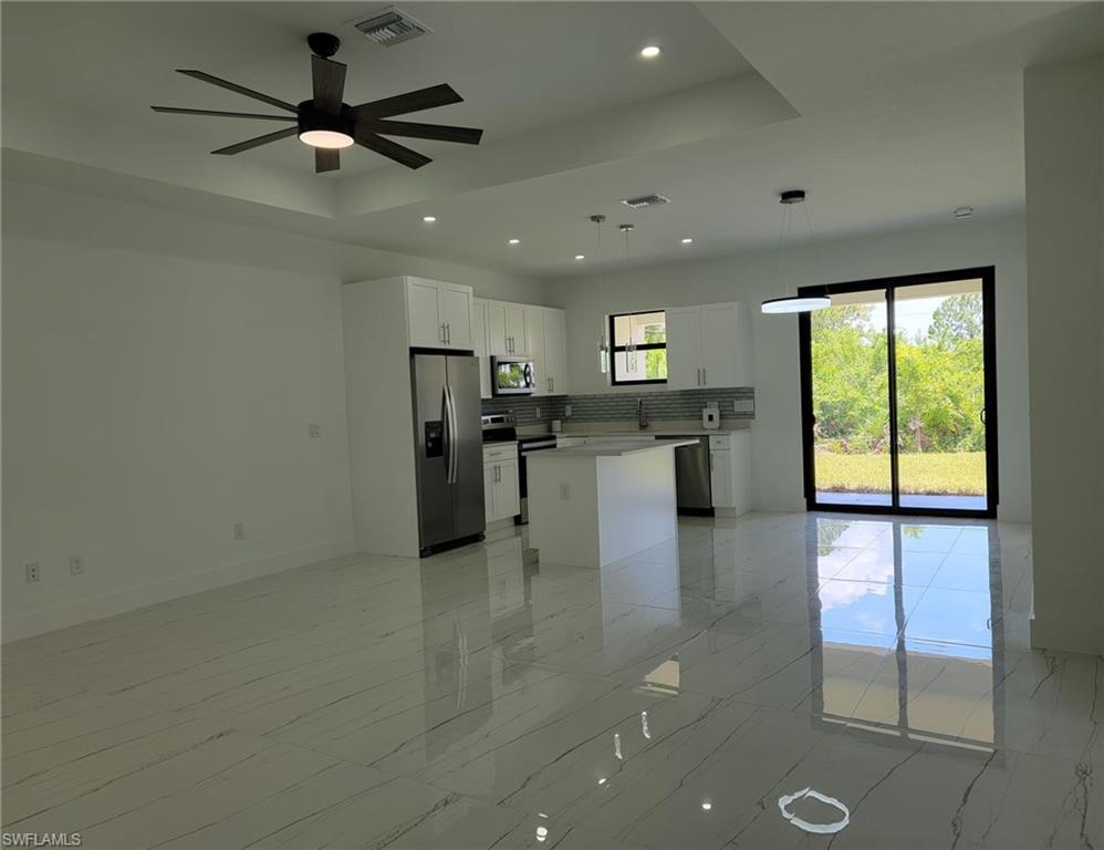 Kitchen with white cabinetry, pendant lighting, stainless steel appliances, and a healthy amount of sunlight