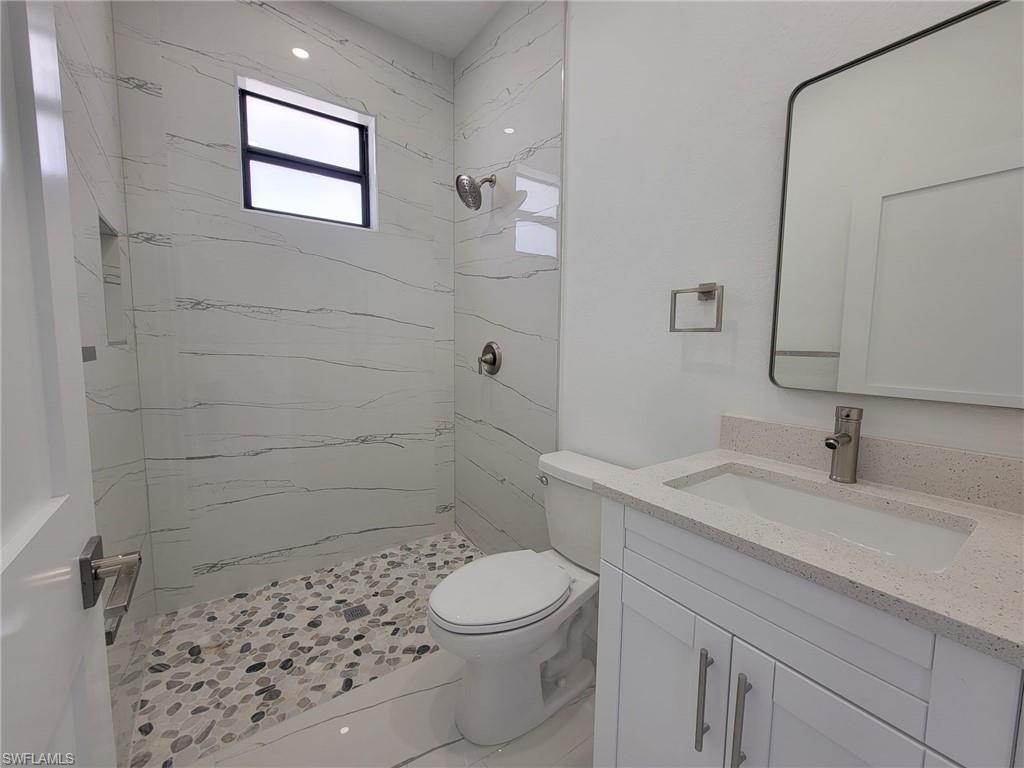 Bathroom featuring vanity, toilet, and a tile shower