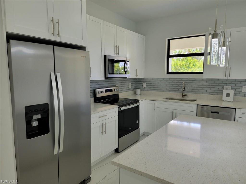 Kitchen featuring sink, stainless steel appliances, backsplash, and white cabinets