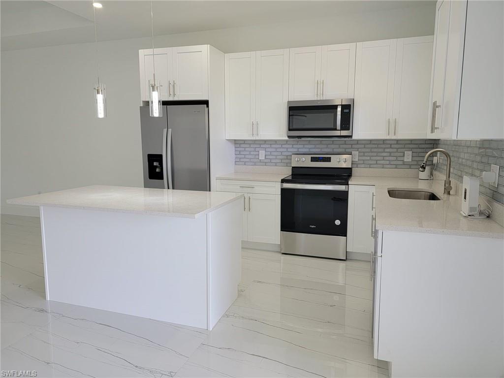 Kitchen featuring white cabinets, stainless steel appliances, a center island, and sink