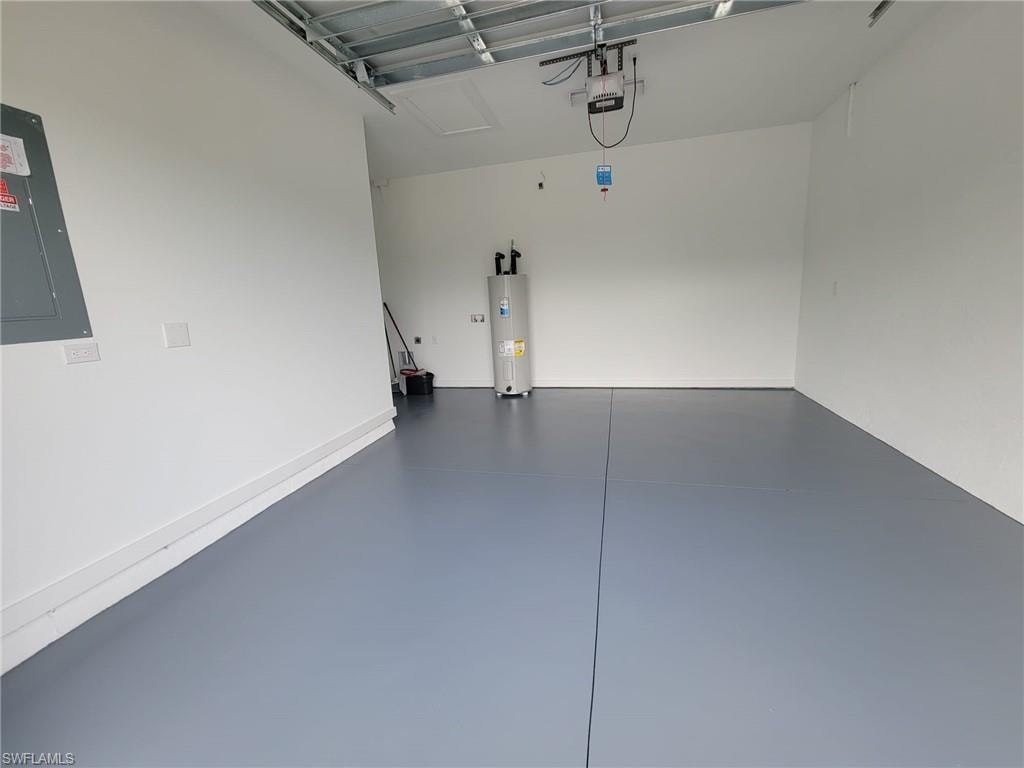 Garage with water heater, electric panel, and a garage door opener