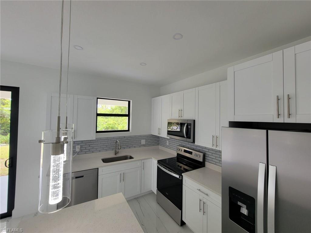 Kitchen with sink, stainless steel appliances, backsplash, and white cabinetry