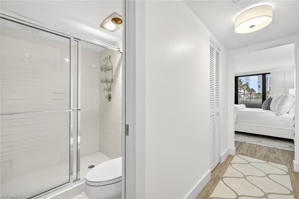 Bathroom featuring a shower stall, connected bathroom, and wood finished floors