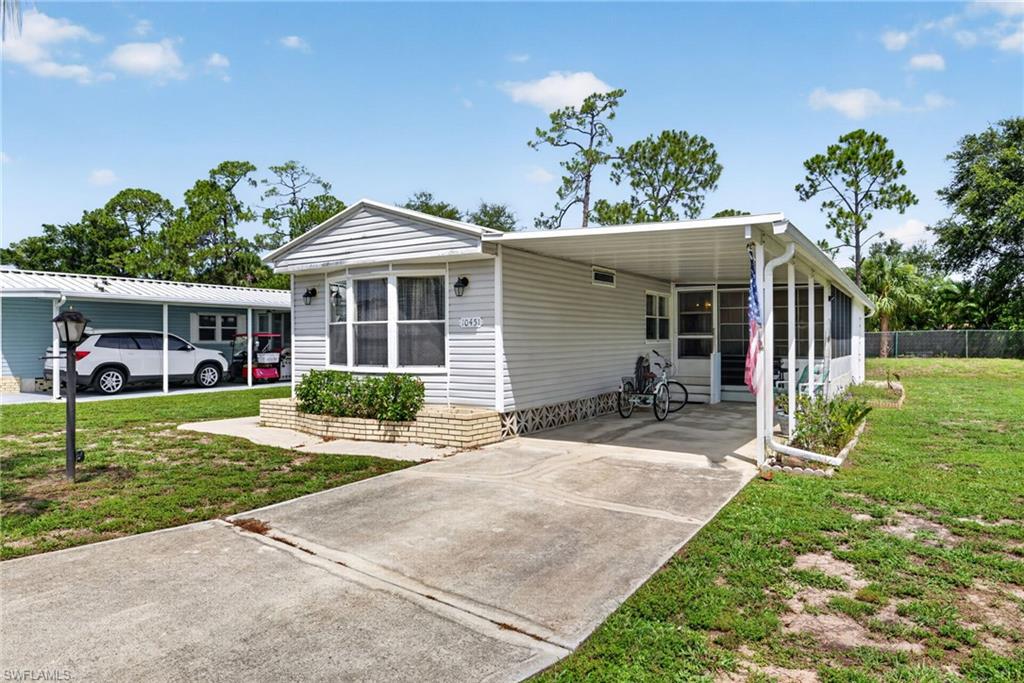 Manufactured home featuring light-colored siding, an attached carport, and a screened-in porch