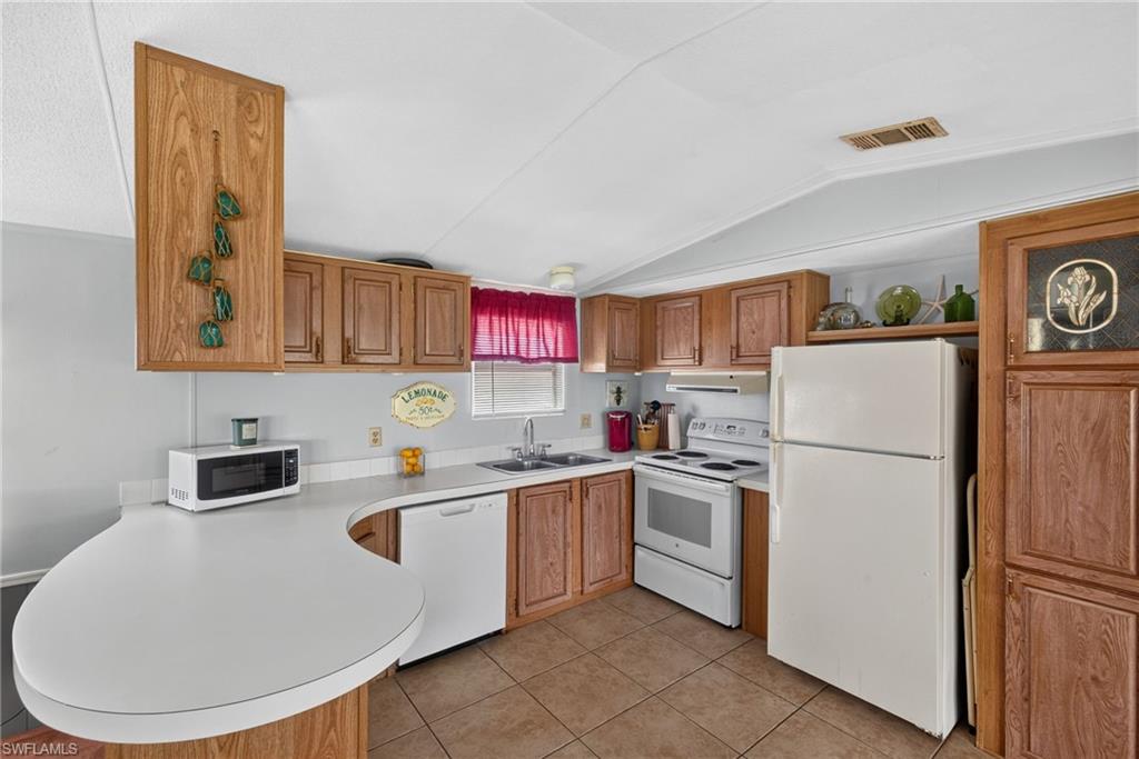 Kitchen featuring wood-finish cabinetry, tile flooring, and a curved breakfast bar