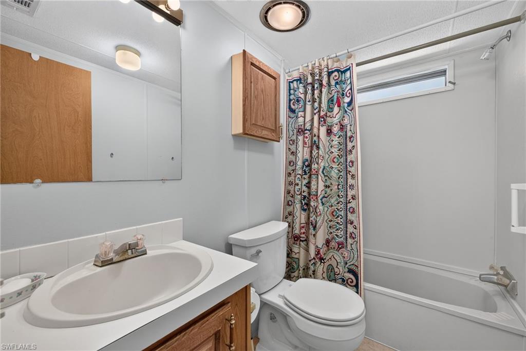 Bathroom featuring an integrated sink with a dual-handle faucet, a large vanity mirror, and a built-in bathtub with a shower fixture