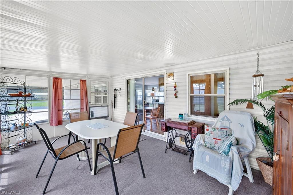 Enclosed patio featuring white horizontal siding, a textured white ceiling, carpeted flooring, multiple windows, and a sliding glass door