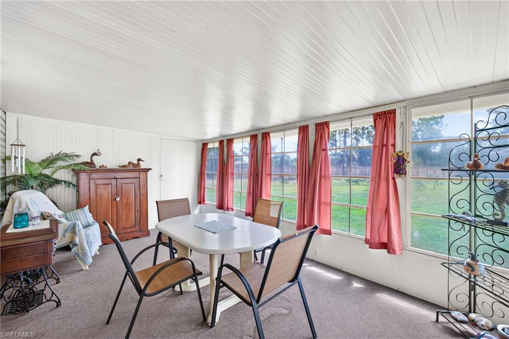 Enclosed sunroom featuring a white paneled ceiling, numerous windows, and carpet flooring