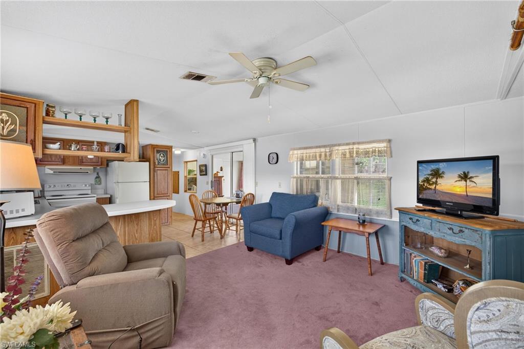 Open-concept living area featuring a kitchen with wood cabinetry, white countertops, and a full suite of appliances