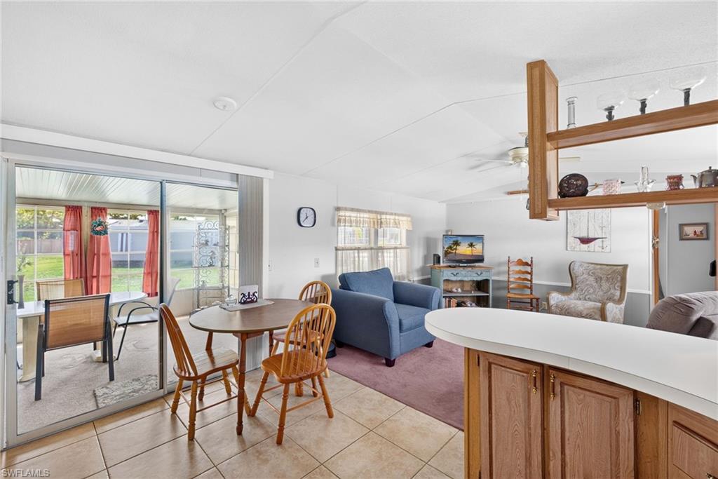 Open-concept living space featuring a breakfast bar with wood-finish cabinetry, tile flooring, and a screened lanai with sliding glass doors