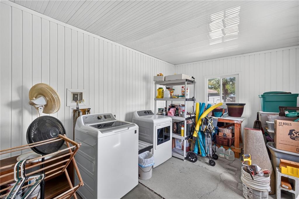 Dedicated laundry area featuring a washer and dryer, board and batten style wall paneling, a window, and durable concrete flooring