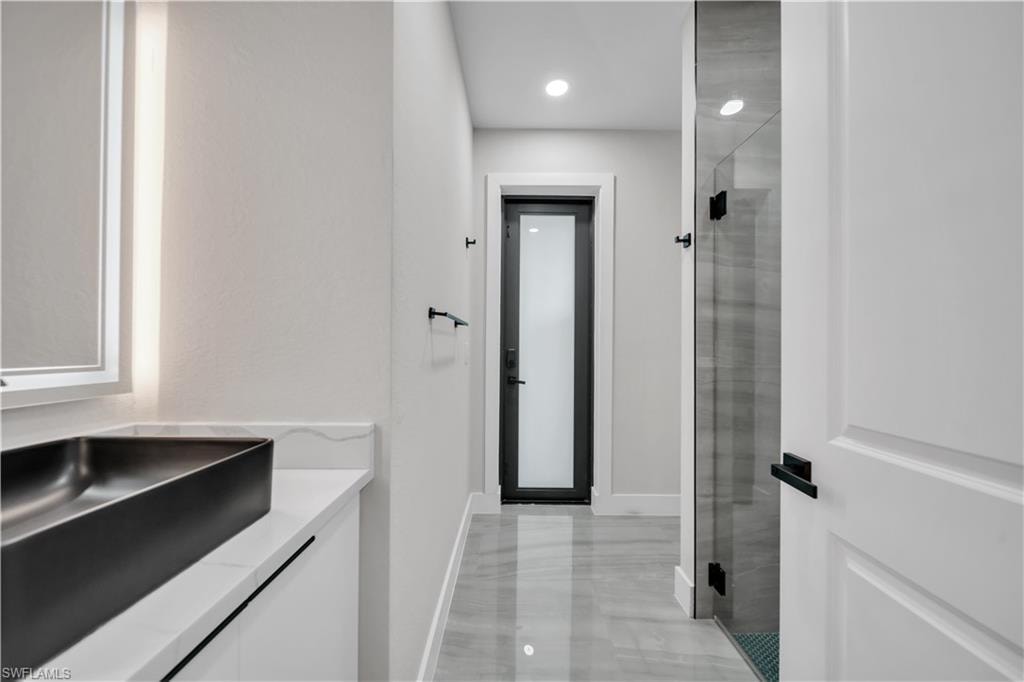 Modern vanity with a black vessel sink, illuminated mirror, and white quartz countertop