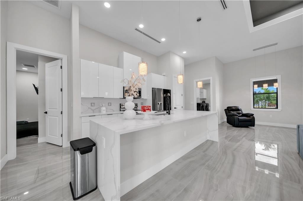 Gourmet kitchen featuring a waterfall island, white cabinetry, integrated appliances, and recessed lighting