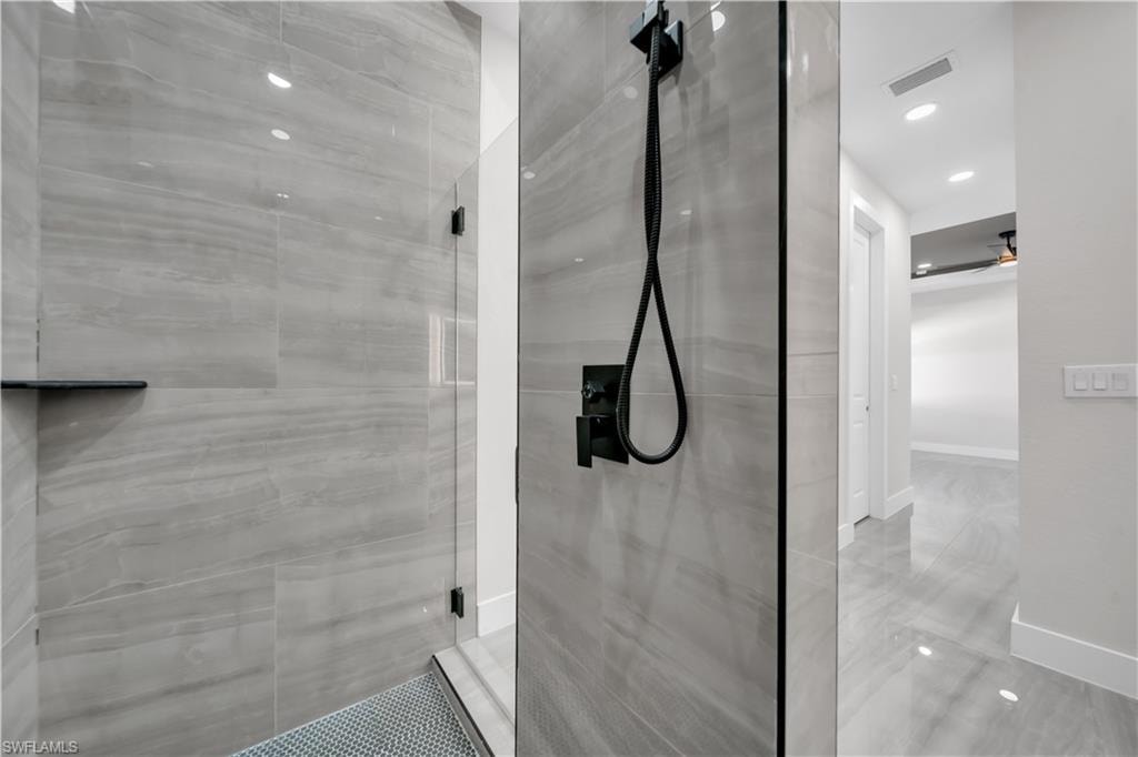 Frameless glass shower with matte black fixtures, integrated shower niche, and mosaic tile flooring