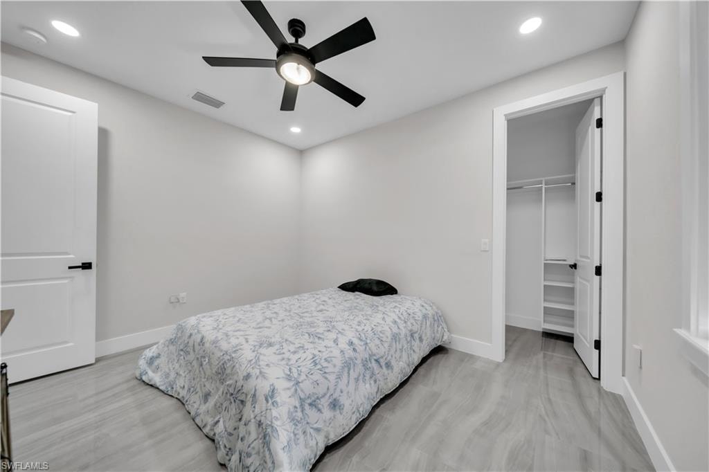 Recessed lighting, ceiling fan with light fixture, wood-finish flooring, white trim, and a closet with built-in shelving