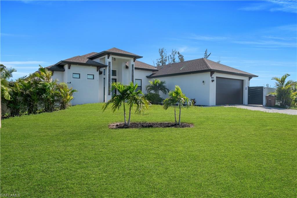 Contemporary residence featuring a stucco exterior, dark roof, two-car garage, and a lush lawn