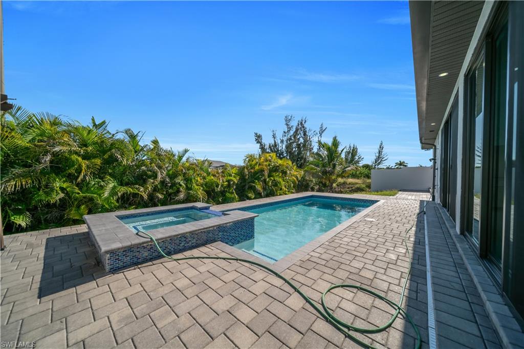 Rectangular swimming pool with integrated spa, surrounded by paver patio