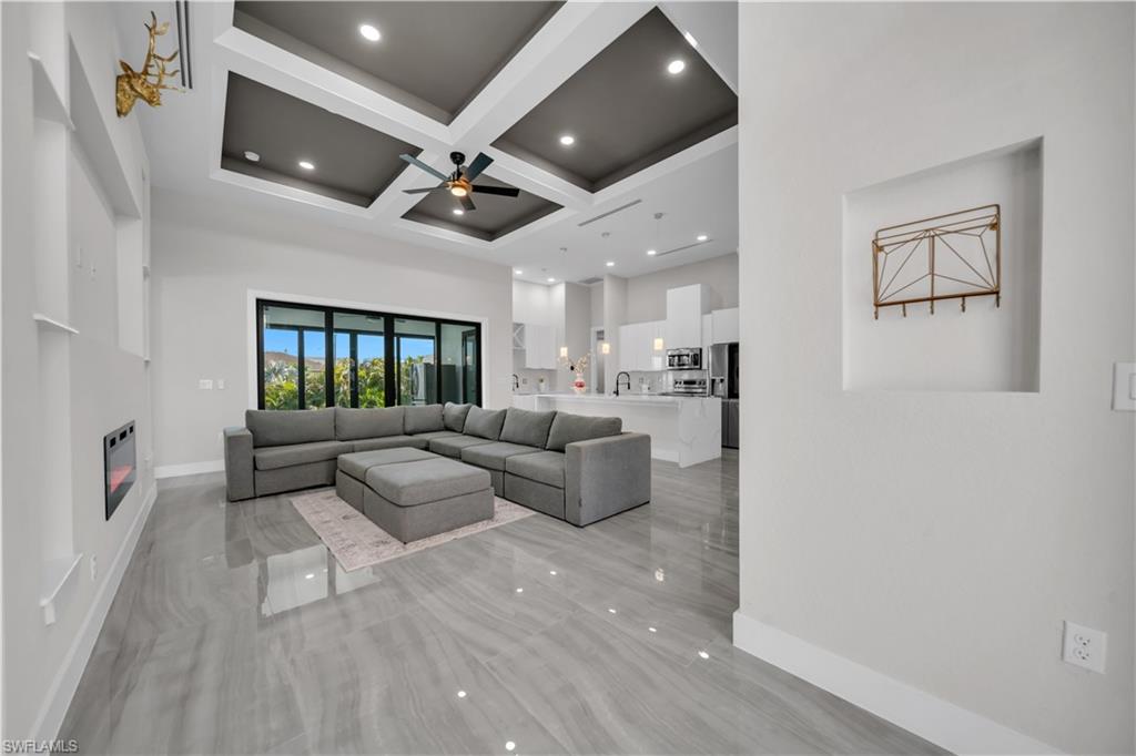 Expansive living area with large format tile flooring, recessed lighting, and a coffered ceiling with a ceiling fan