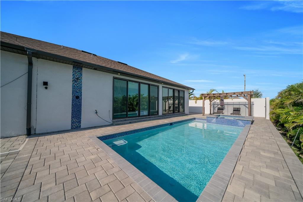 Backyard oasis featuring a swimming pool, integrated spa, and paver decking