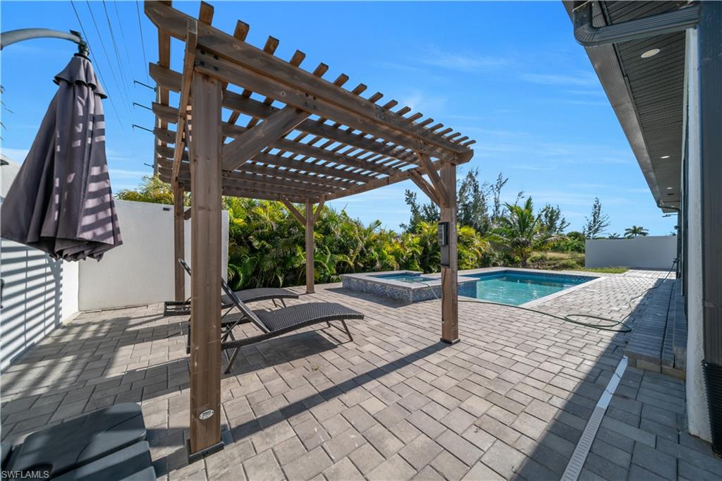 Paver patio featuring a wooden pergola, an in-ground swimming pool, and an integrated spa