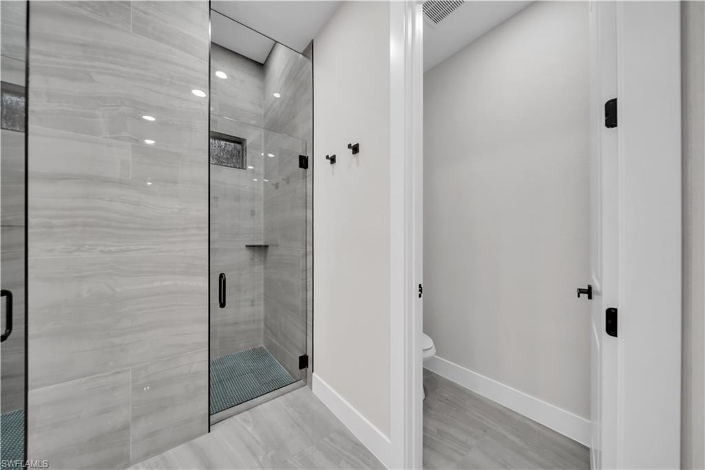 Glass-enclosed shower with a built-in niche and light gray tile flooring