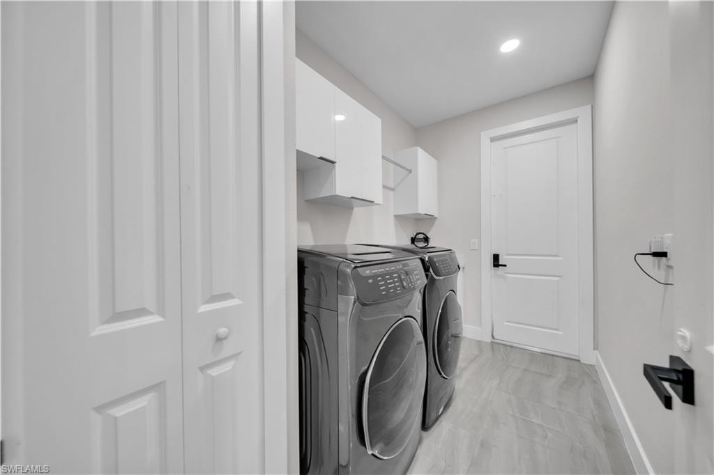 Built-in white cabinetry, recessed ceiling lighting, light-toned plank flooring, and a solid white door with a black lever handle