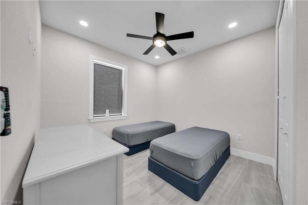 Recessed lighting, ceiling fan with light fixture, window with roller shade, wood-finish flooring, and bi-fold closet doors