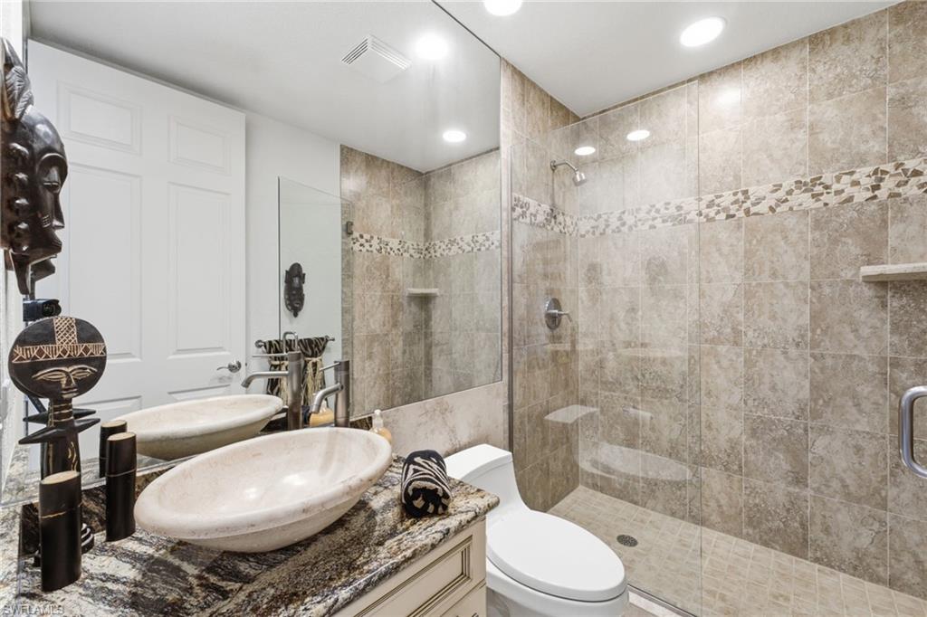 The third full bathroom is conveniently located just outside the second bedroom and offers a beautifully appointed design with a striking vessel sink, elegant granite countertop, and a luxurious walk-in shower featuring a seamless glass enclosure. Floor-to-ceiling tile and exquisite listello accents create a sophisticated spa-like retreat with timeless appeal.