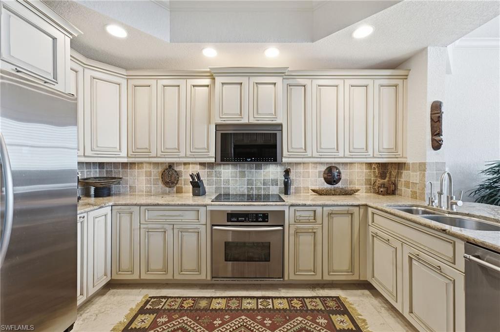 The kitchen is further enhanced by elegant recessed lighting and a sophisticated tray ceiling, adding architectural depth and a warm, inviting ambiance to this beautifully designed culinary space.