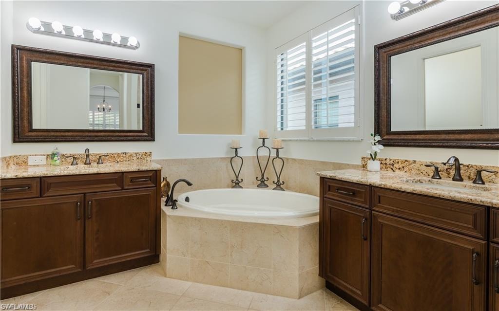 Bathroom featuring two vanities, a garden tub, and light tile patterned floors