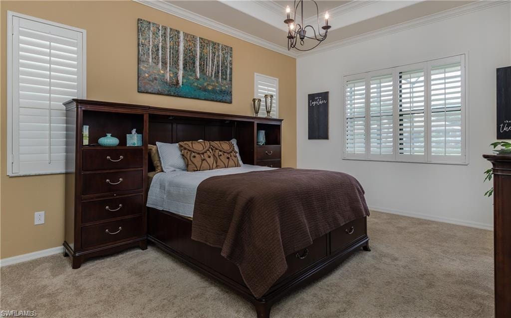 Bedroom featuring ornamental molding, a chandelier, light carpet, and a tray ceiling