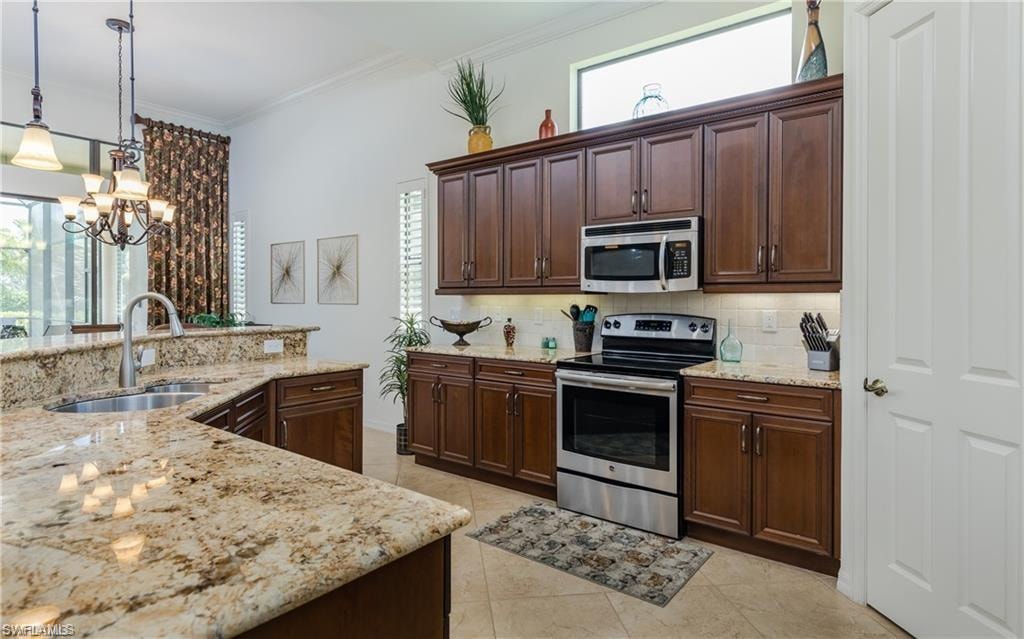 Kitchen featuring dark brown cabinets, appliances with stainless steel finishes, tasteful backsplash, light stone counters, and crown molding