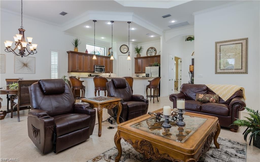 Living area with crown molding, a chandelier, and a high ceiling