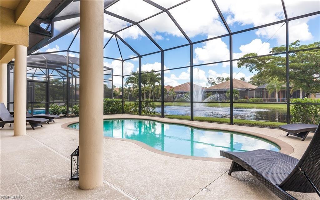 Outdoor pool featuring a sunroom, a patio, glass enclosure, and a water view