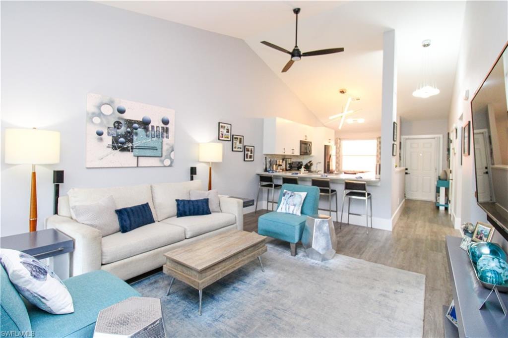 Living room with light hardwood / wood-style floors, high vaulted ceiling, and ceiling fan