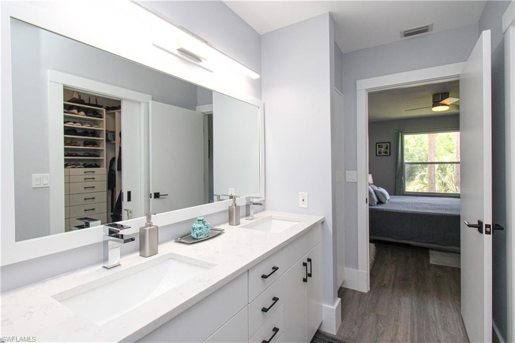 Bathroom featuring ceiling fan, double sink vanity, and wood-type flooring
