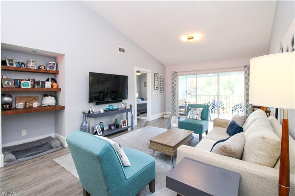Living room with high vaulted ceiling and hardwood / wood-style floors