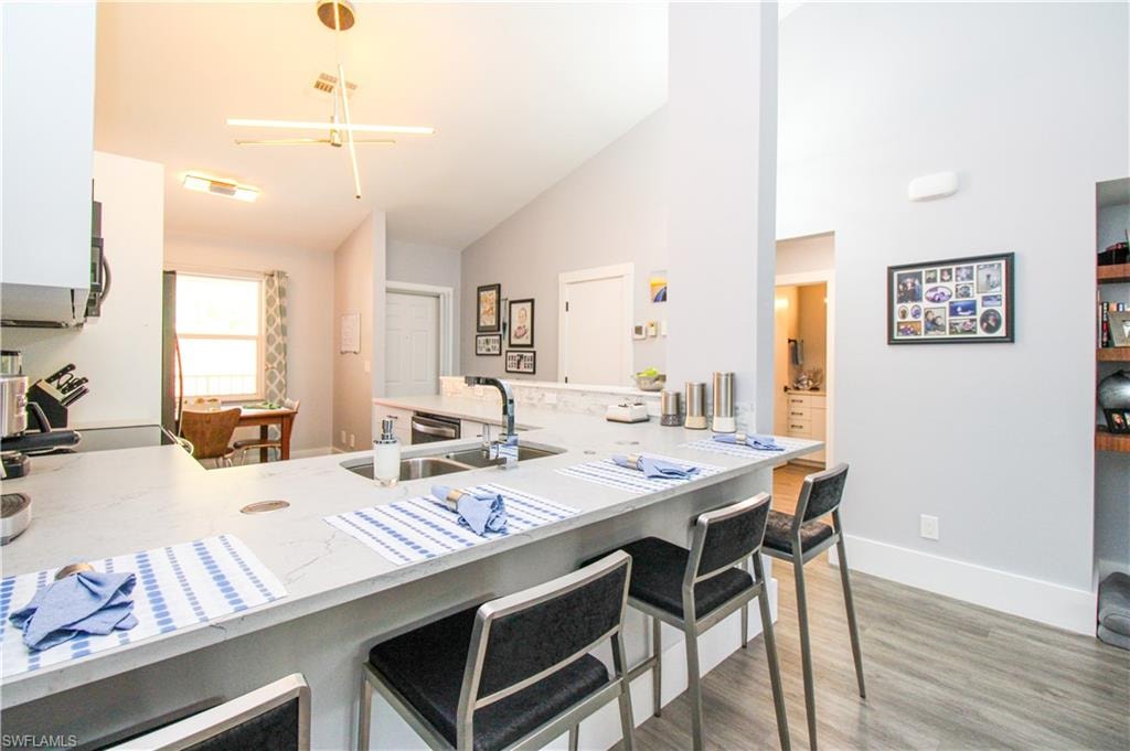 Kitchen featuring sink, hardwood / wood-style flooring, a breakfast bar area, and kitchen peninsula