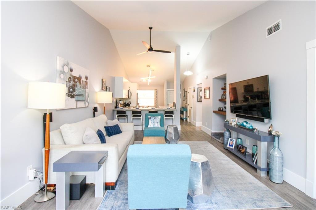 Living room featuring high vaulted ceiling, hardwood / wood-style flooring, and ceiling fan