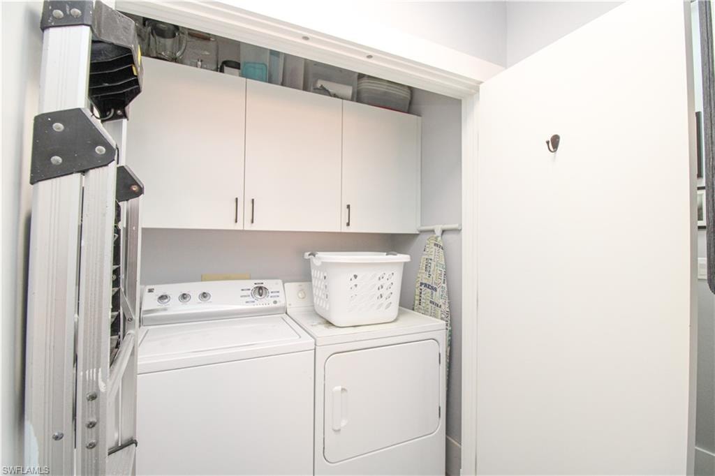 Laundry room with washer and clothes dryer and cabinets