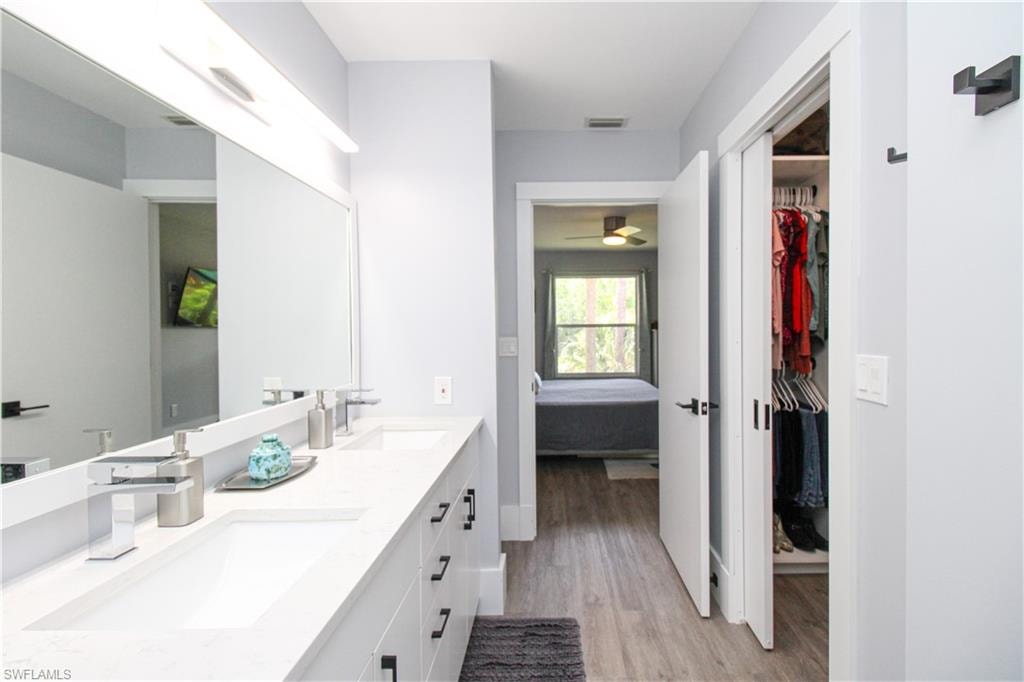 Bathroom featuring dual bowl vanity, ceiling fan, and wood-type flooring