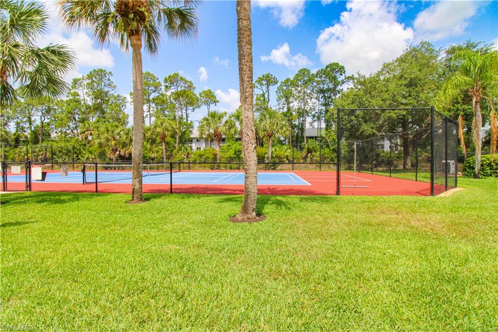 View of home's community with a lawn and tennis court
