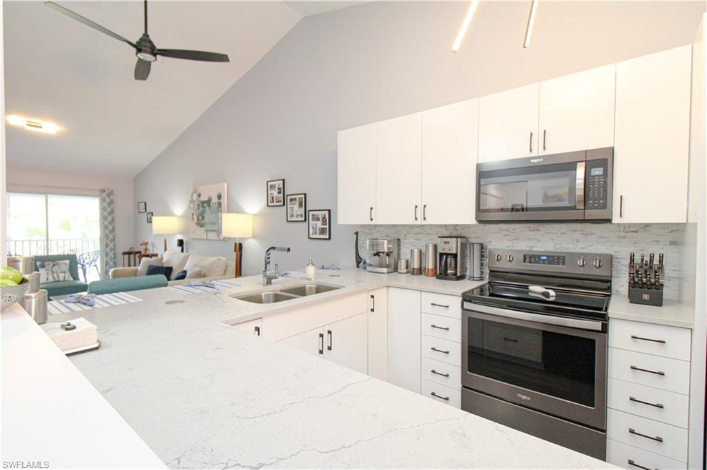 Kitchen featuring sink, tasteful backsplash, white cabinetry, and appliances with stainless steel finishes