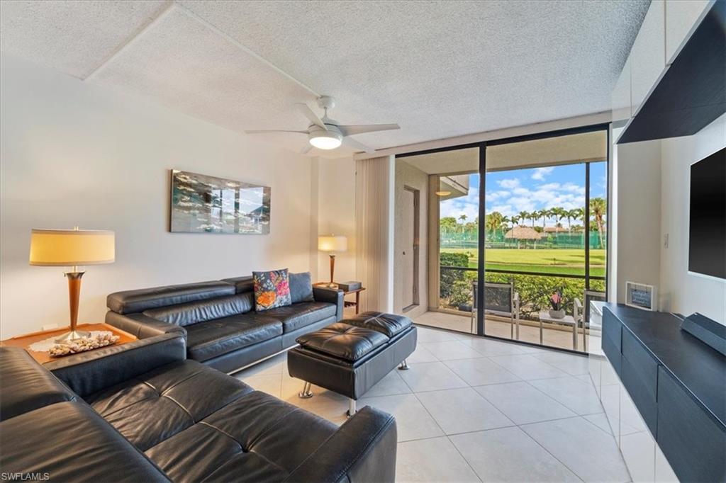 Living room with floor to ceiling windows, a textured ceiling, light tile patterned floors, and ceiling fan