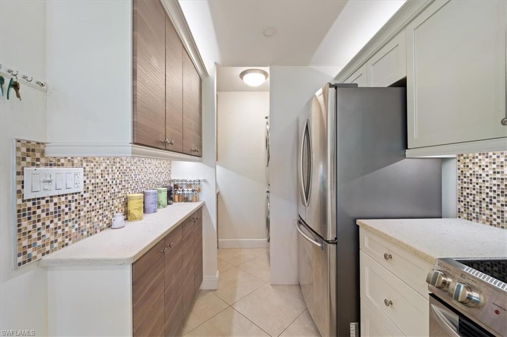 Kitchen featuring tasteful backsplash, appliances with stainless steel finishes, light tile patterned floors, and light stone countertops