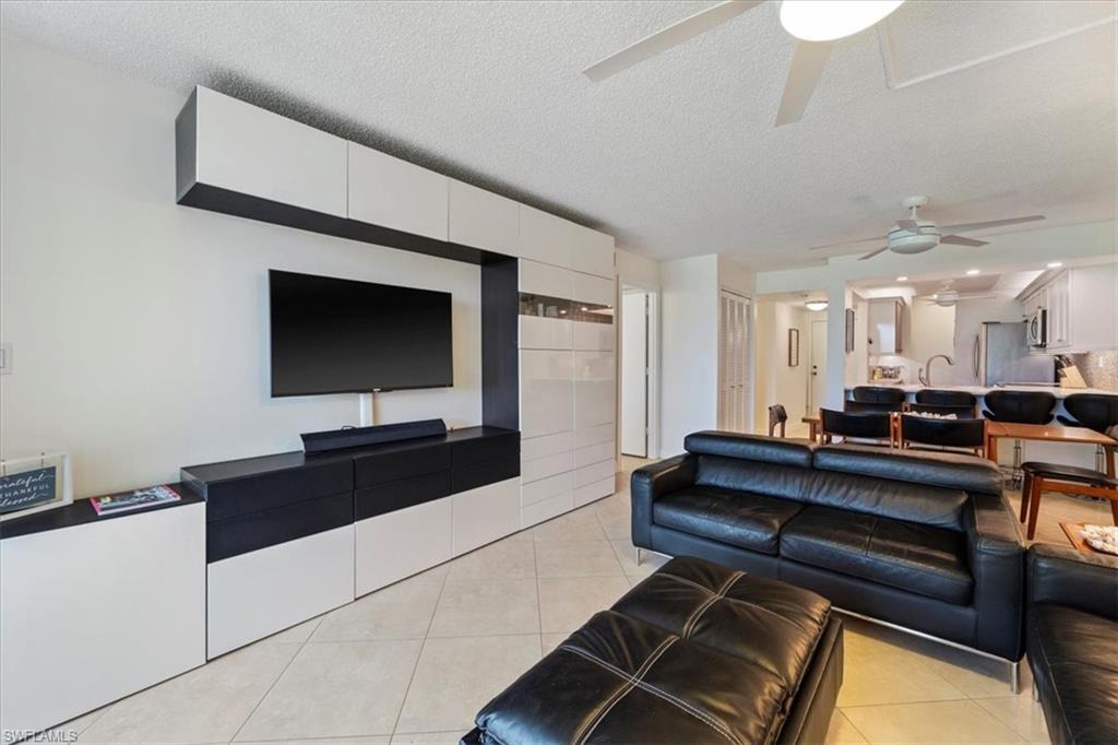 Living area with a textured ceiling, light tile patterned floors, and a ceiling fan